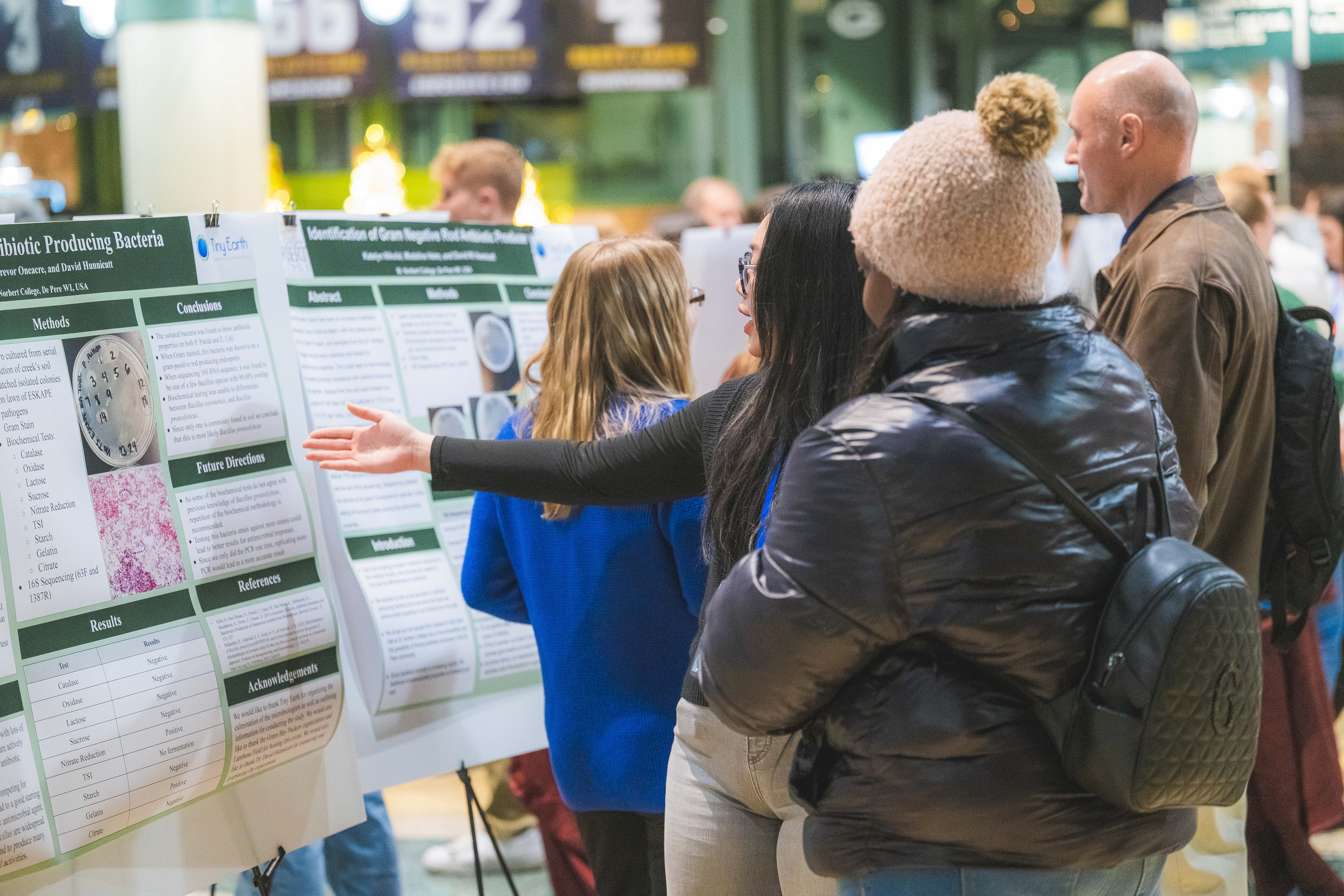 A student from Saint Norbert College explains their research poster to a visitor