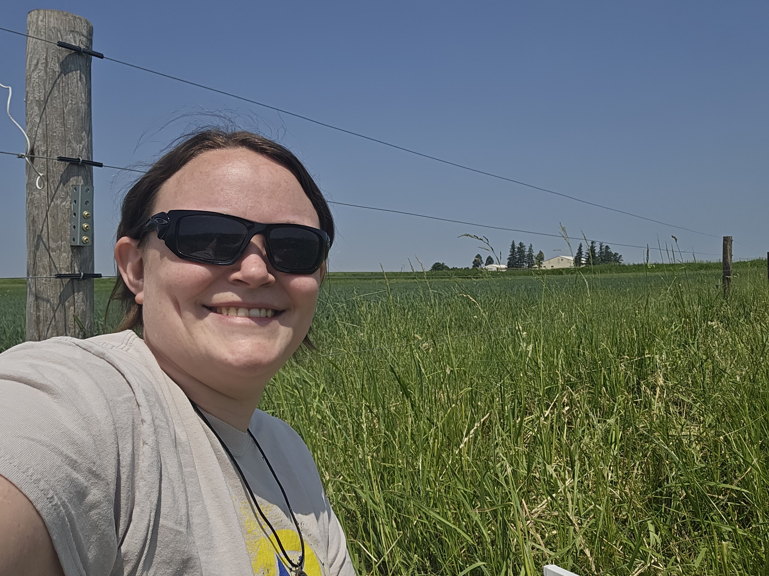 Tasha Miller taking a selfie in a research field where she collects her plant data.